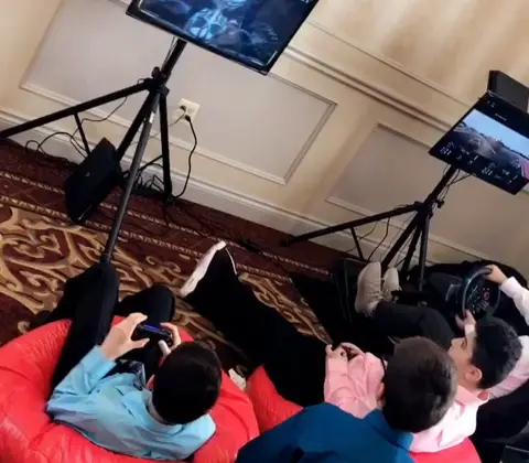 Kids on red bean bags playing consoles on mounted screens