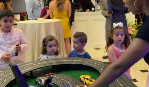 Children racing slot cars around a turf track