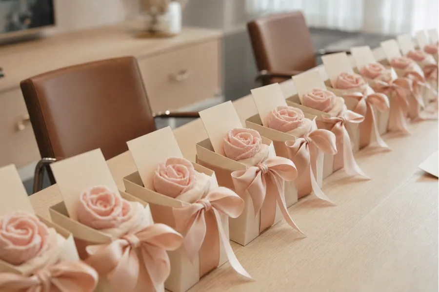 Row of small gift boxes, each holding one marshmallow rose